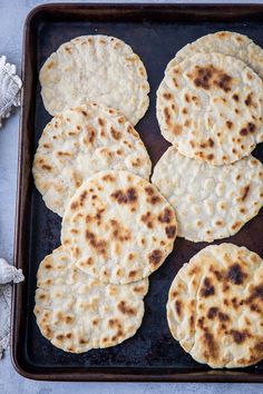 four flat breads on a baking sheet ready to be cooked in the oven for dinner