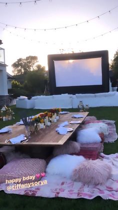 an outdoor movie is set up in the grass with fluffy pillows and blankets on it