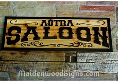 a wooden sign hanging on the side of a brick wall that says astra saloon