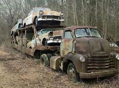 an old rusty truck is sitting in the middle of a field next to another rusted car