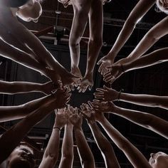 a group of people holding their hands together in a circle with the light shining on them