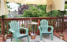 two lawn chairs sitting on top of a wooden deck next to an umbrella and potted plant