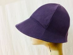 a mannequin's head wearing a purple hat on top of a white background