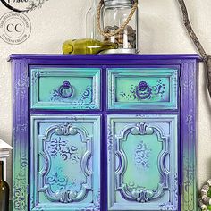 a blue and green dresser with bottles on it's top next to other items