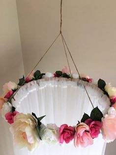 a flower wreath hanging from the ceiling in front of a white fan with pink and white flowers