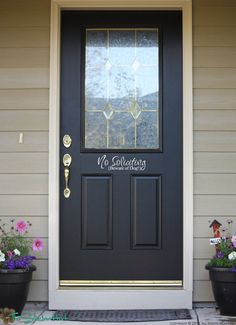 a black front door with two flower pots on the side