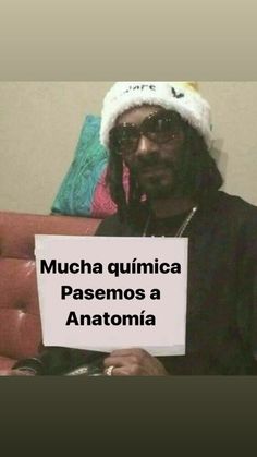 a man sitting on a couch holding a sign that says mucha quimica pasoemos a anatomia