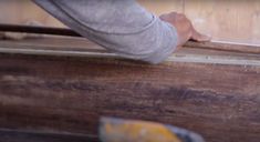 a person holding onto a piece of wood with a hammer in their left hand and on top of it