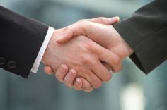 two people shaking hands in front of a building