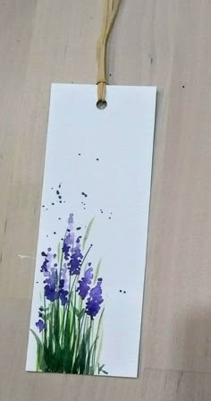 a piece of paper with some purple flowers on it and a string attached to it