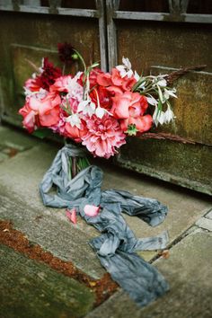 a bouquet of flowers sitting on the ground next to an open door with ribbon tied around it