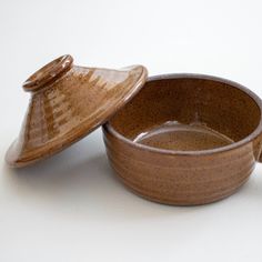 two brown bowls sitting next to each other on a white surface