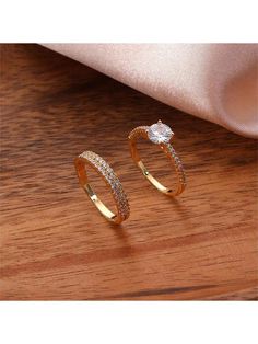 two gold rings sitting on top of a wooden table