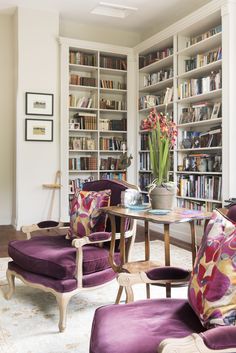 a living room filled with lots of bookshelves next to a table and chairs