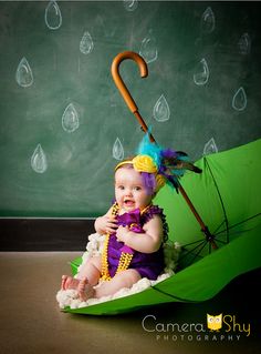 a baby sitting on the ground in an umbrella