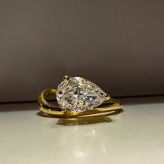 a pear shaped diamond ring sitting on top of a counter