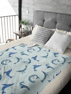 a bed with a blue and white comforter on top of it next to pillows