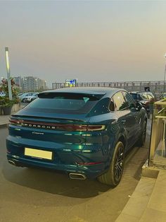 a blue porsche cayen is parked on the side of the road with other cars