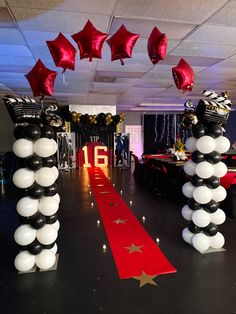 balloons and streamers decorate the entrance to a party with black, white and red decorations