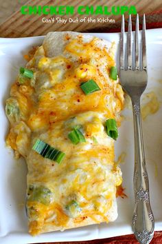 a white plate topped with an enchilada covered in cheese and green onions