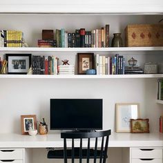 a desk with a computer on top of it and lots of books in the shelves