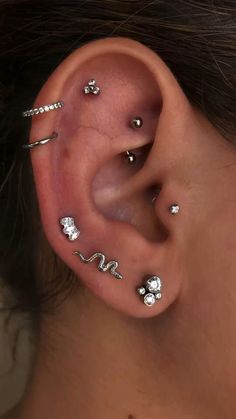 a woman's ear with several different piercings on the top and bottom of it