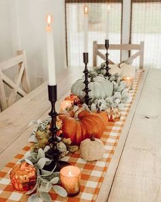 a long table with candles and pumpkins on it