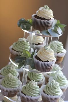 cupcakes with frosting and greenery are stacked on top of each other