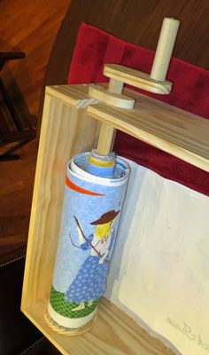 a wooden shelf with a blue and white vase on it's side next to a red chair