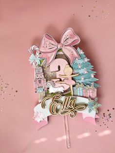 a pink cake topper with a bow on it's head and the word gly written in gold