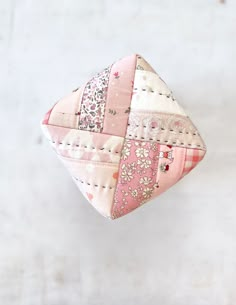 a pink patchwork pillow hanging on a white wall