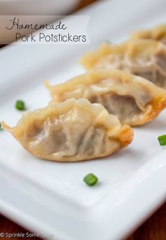 two small dumplings on a white plate with green onions and meat in the middle