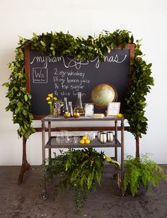 a blackboard with writing on it next to some potted plants and other items