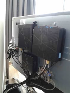 two computers sitting on top of each other in front of a computer monitor with wires attached to it