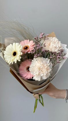 a person holding a bouquet of flowers in their hand with grass and pink and white flowers