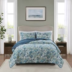 a bed with blue and white comforters in a room