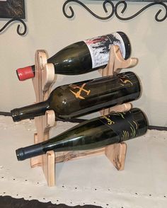 three wine bottles are sitting on a wooden rack that is attached to a white wall