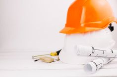 an orange hard hat sitting on top of a white table next to paint rollers