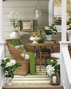 an outdoor dining area with wicker chairs and white flowers in vases on the table