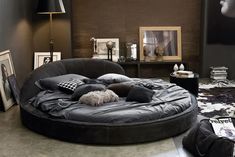 a large round bed in a living room with black furniture and decor on the walls