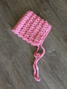 a pink crocheted hat laying on top of a wooden floor