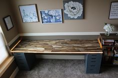 an office desk with drawers and pictures on the wall