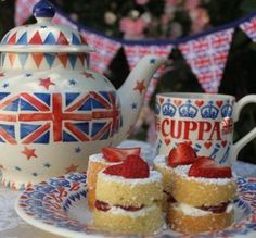 two small cakes on a plate next to a teapot and flag bunt cake