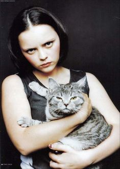 a woman holding a cat in her arms with the caption, i am not sure what this image is