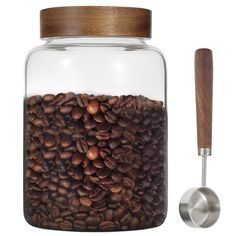 a glass jar filled with coffee beans next to a spoon