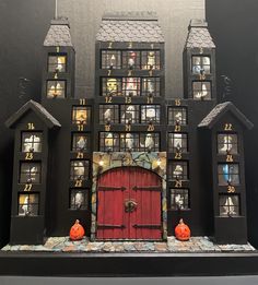 a black and red house with pumpkins on the front door, windows and clock