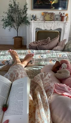 a person laying in bed with their feet up on an open book next to a fireplace