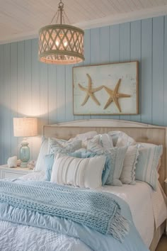 a bedroom with blue and white bedding, starfish on the wall above it