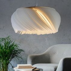 a modern light fixture hanging over a table next to a chair and potted plant