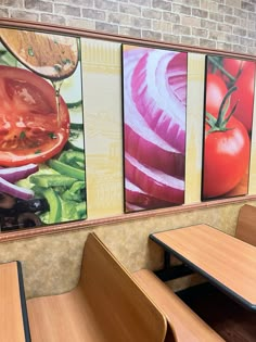 some tables and benches in a restaurant with pictures on the wall behind them that have vegetables painted on them